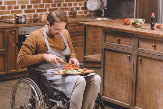 high angle view of disabled man in wheelchair cutting vegetables at home