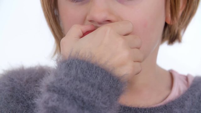 A young girl is tasting a bit of the red apple and then she is spitting it out.