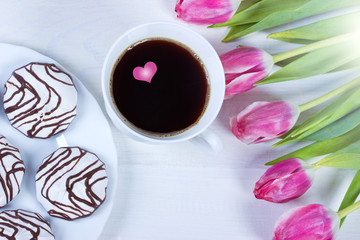 Cup with coffee and tulips on white wooden table