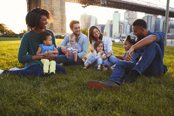 Two families with daughters sitting on lawn