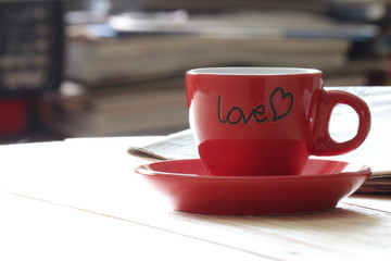 Red coffee cup with news paper in coffee shop.