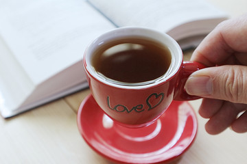 Red coffee cup with book in coffee shop.