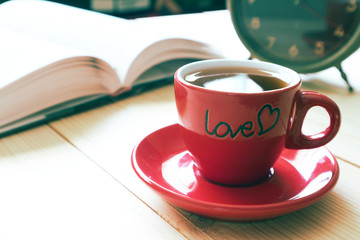 Red coffee cup with background book and clock.
