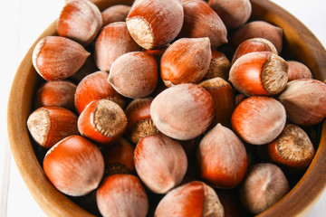 Hazelnut nuts in a wooden bowl on a white wooden table. Superfood.