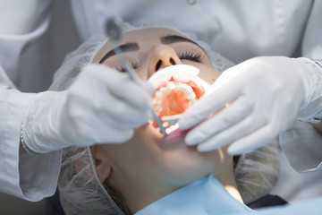 Young female patient visiting dentist office.Beautiful woman with healthy straight white teeth sitting at dental chair with open mouth during a dental procedure.Dental clinic. Dental caries