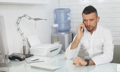 Handsome businessman working at computer. Portrait of young man sitting at his desk in the office