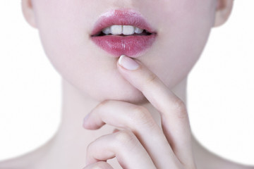 Close up of a young woman's pink lips with white teeth and hand gently touching her chin on white background