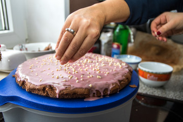 Glühweinglasur auf Kuchen, Frau streut gehackte Mandeln darüber
