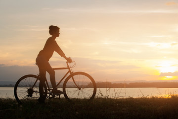Fototapeta na wymiar girl riding bicycle at sunset or sunrise background