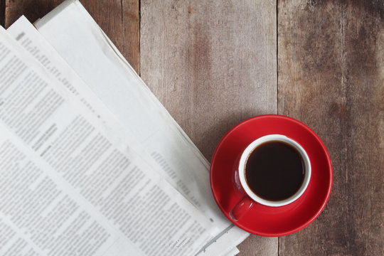 Red coffee cup and news paper on wood table