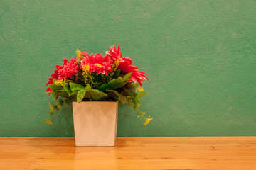 Fake flowers in pot with green background.