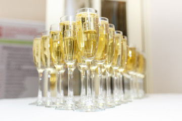 lot of blurred glasses with champagne on the reception party table on light background