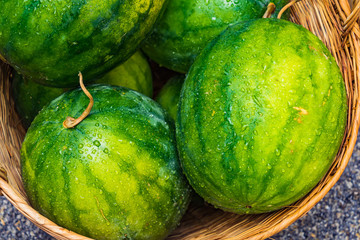 Fresh Watermelon in a basket, green and yellow watermelons in the market background