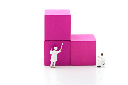 Miniature people: Two worker painting ultra violet wood cube with copy space using as background business concept.