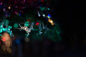 Obraz na płótnie Canvas Christmas decoration crystal doll deer shaped on Christmas tree with fir, bell, ribbon and bokeh background, beautiful at night for celebration