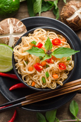 Instant noodles in black bowl on wooden background.