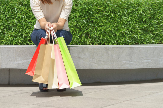 Close up of woman customer sitting and holding colorful paper shopping bags