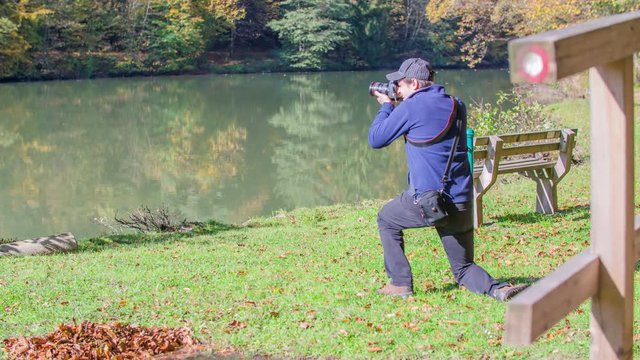 A photographer is taking a photos of the lake. It's a nice autumn day.