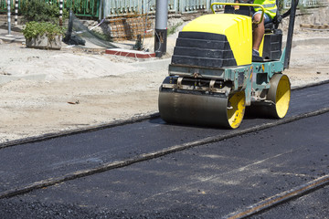 Steamroller construct asphalt road and railroad lines