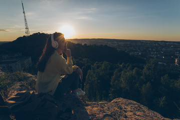 young pretty woman listing music on the top of the hill