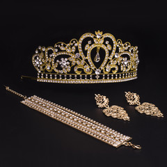 set of crown, earrings, bracelet isolated on black