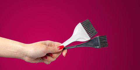 Woman hand with a hair dresser's tools and accessories isolated on color background