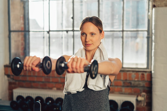 Determined woman exercising with dumbbells