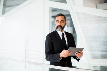 Fototapeta premium Handsome middle age businessman with digital tablet in the modren office