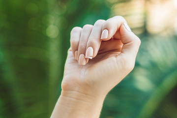 Broken nail on a woman's hand with a manicure on a green background
