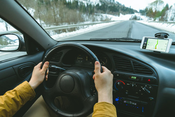 Driver's hands on a steering wheel and blurred road