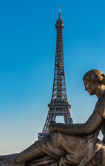 Eiffel Tower behind the statue of a seated woman