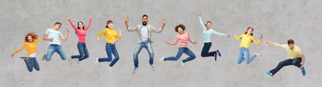 happy people or friends jumping in air over gray