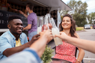 friends clinking bottles with drinks at food truck