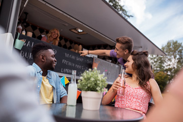 friends with drinks sitting at table at food truck