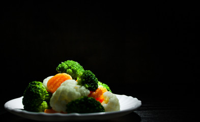 Mixed vegetables. cauliflower, broccoli and carrots in plate on the old dark wooden background with copy space