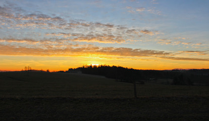 Famous gold winter sunrise on Czech countryside with dark landscape silhouette