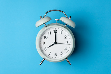 vintage alarm clock on the middle of solid light blue color background