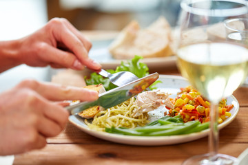 hands of woman eating pasta with chicken meat