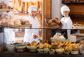 Smiling women selling fresh pastry and loaves