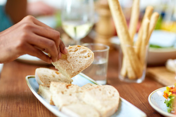 hand taking piece of bread from plate