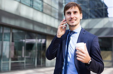 Cheerful male standing outdoor and talking phone