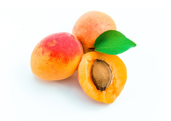 Fresh ripe apricots, whole and half, with leaves, on white background.
