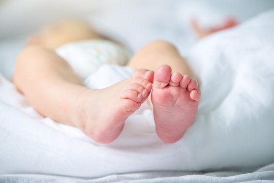 Baby feet with pink lying on a white blanket. Concept of tenderness and motherhood