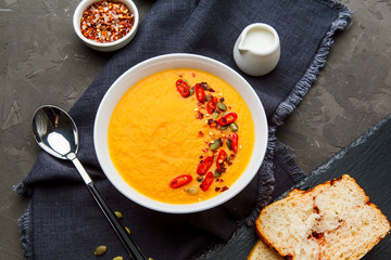 Pumpkin soup in white plate with spice on dark background