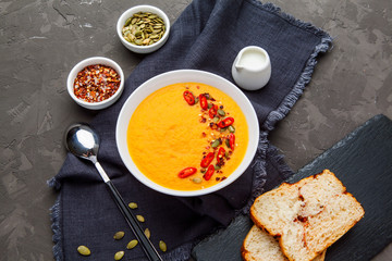 Pumpkin soup in white plate with spice on dark background