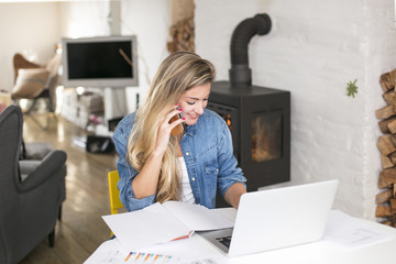 Obraz premium Young beautiful woman works on computer from a home with a laptop on a white desk as a freelancer