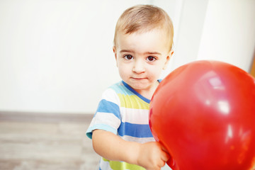 Fototapeta na wymiar Little boy holding red balloon