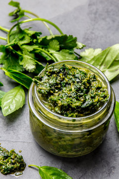 Chimichurri sauce. Argentine green parsley basil sauce chimichurri for barbecue asado in glass jar, gray slate background