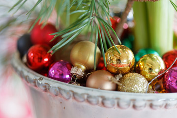 Colorful red christmas ball decorations in a bowl with a branch of pine