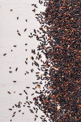 Black dry rice. On a wooden background. Top view. Copy space.